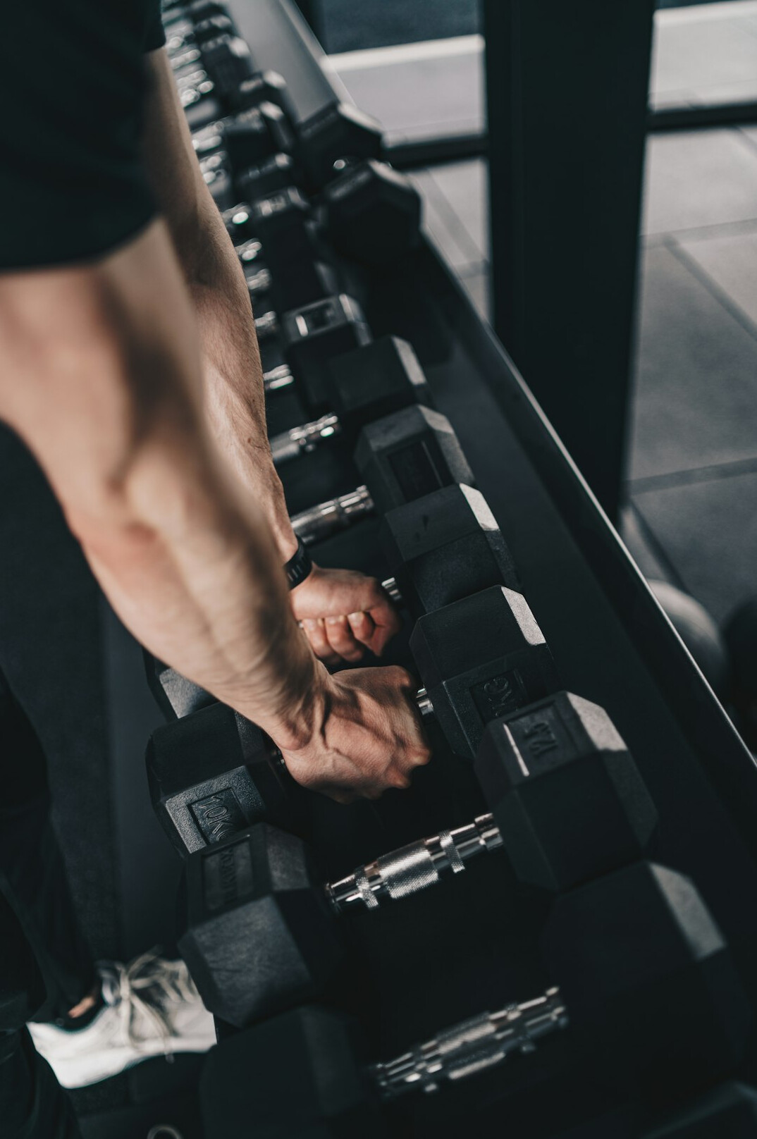Person lifting dumbbells in a bright gym